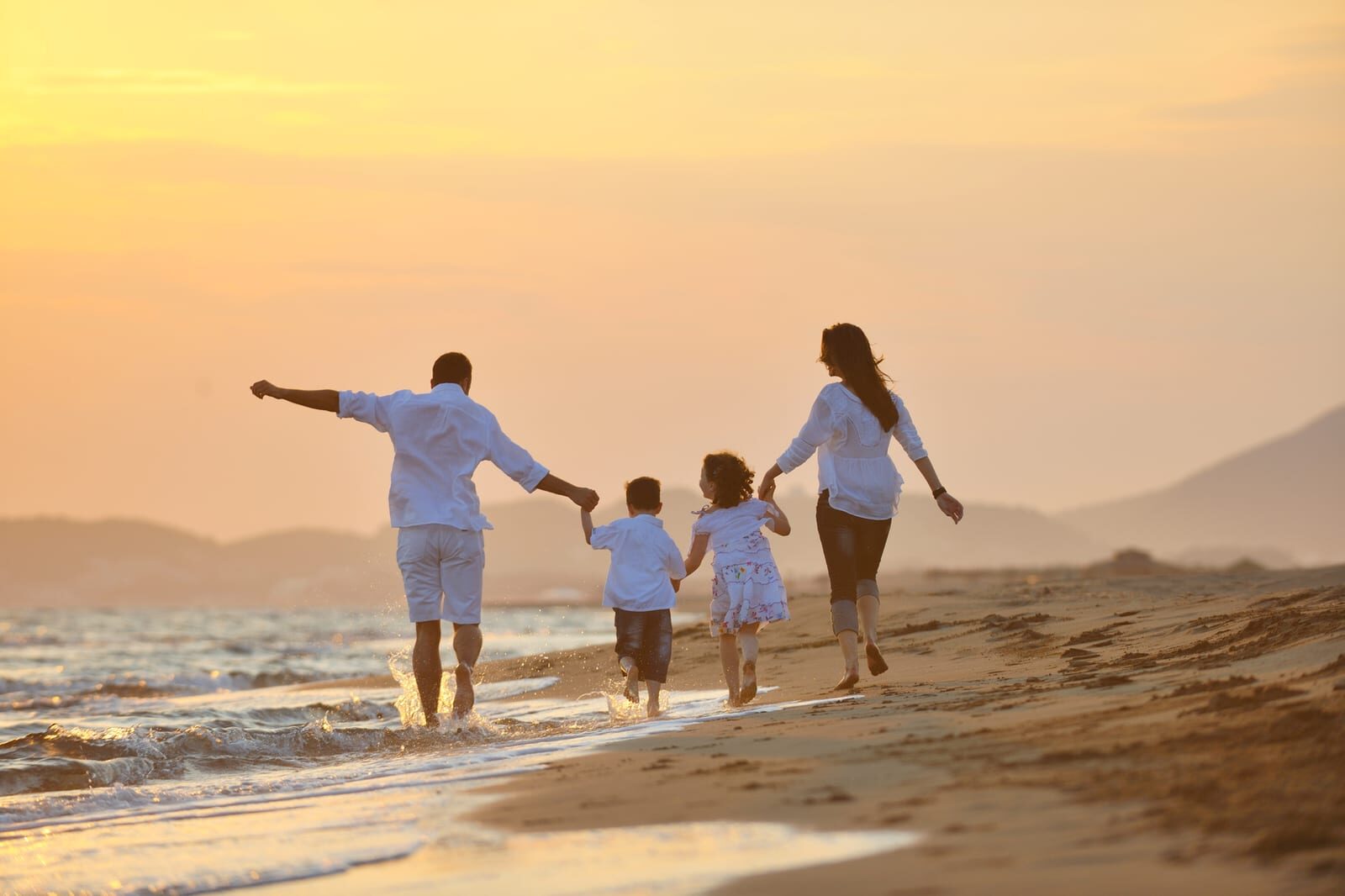 A family walking together along a beach at sunset